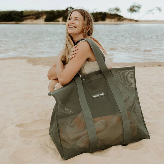 Girl with large olive green mesh bag on shoulder at lake.