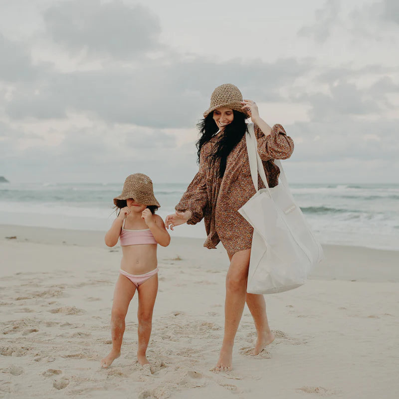 A Mum and child on beach carrying large beach bag